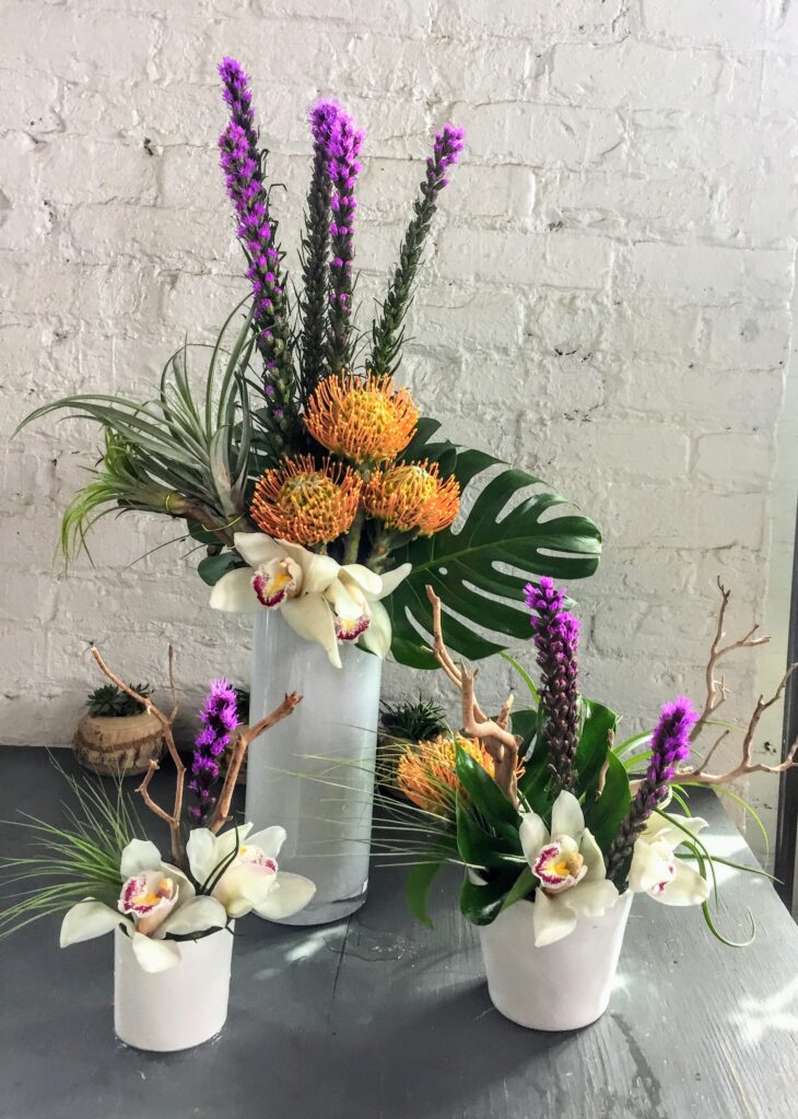 Three floral arrangements on a table, ranging from small, medium, and large sizes.