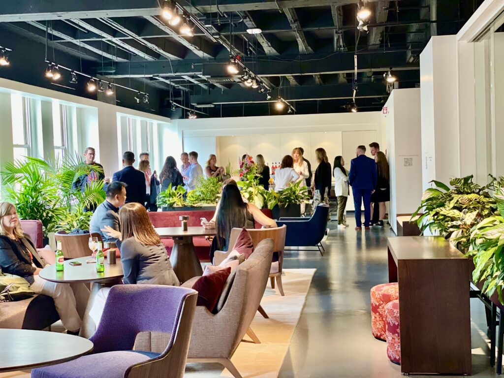The HBF Showroom. There are people gathered drinking beer sitting on and around furniture with Khloros plants placed around